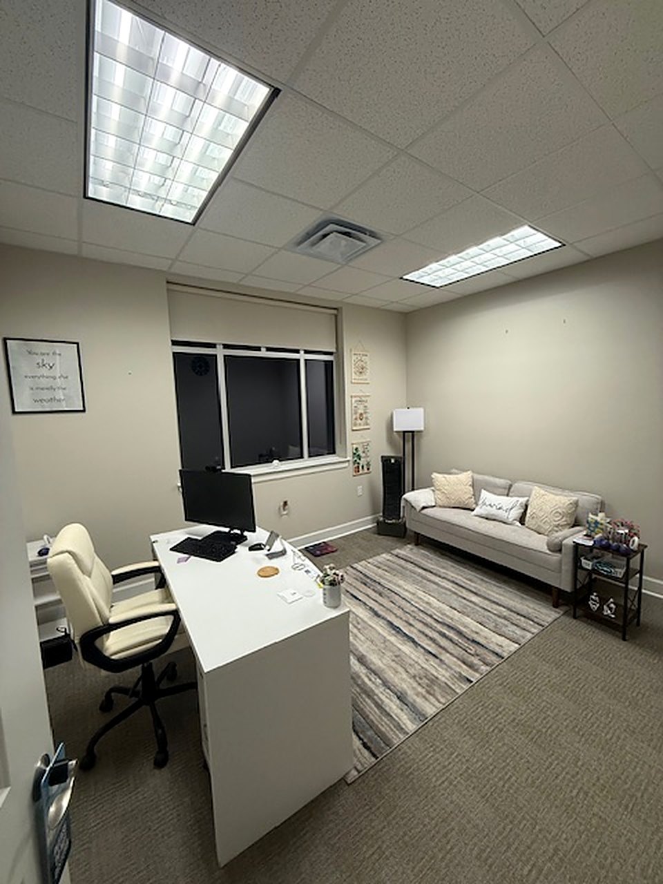 A consultation room with a sofa, a desk and a window